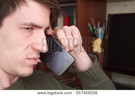 Young Guy Talking On A Black Smartphone With A Smile, Good News