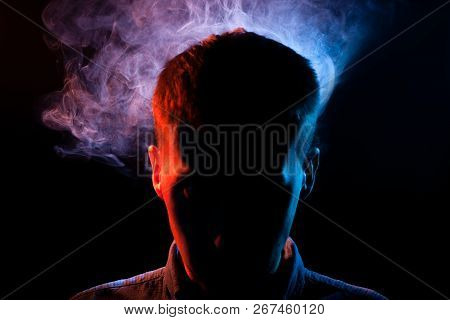 The Man's Face Is Hidden In The Shadows On A Black Isolated Background With Red And Blue Smoke From 