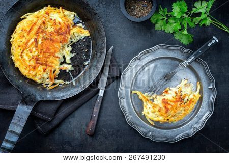 Traditional Swiss rosti as side dish with leek as top view in a frying pan and a pewter plate 