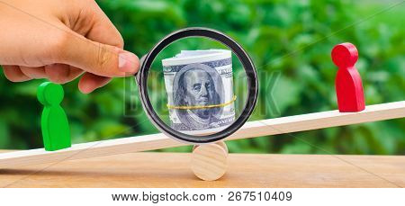 Wooden Figures Of People On Scales And Dollars Between Them. A Dispute Between Two Businessmen. Tria