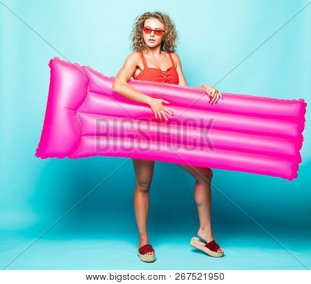 Full Length Portrait Of A Young Curlu Woman In Red Bikini Holding A Swimming Pink Mattress Against G