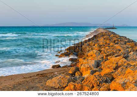 Long Stony Spit Going Far To Sea In Heraklion City On Crete, Greece. Roaring Waves Batter Against Th