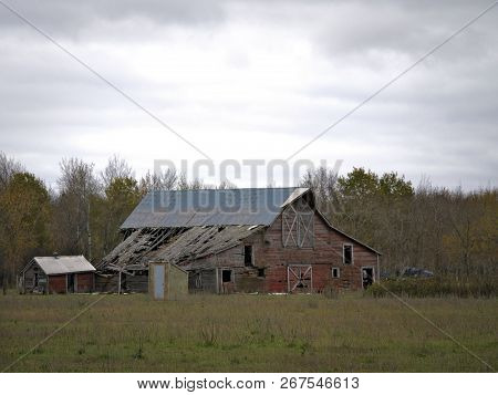 Drab Abandoned Dilapidated Farm Barn And Shed With Clouds In Northern Minnesota
