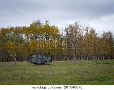 Abandoned Dilapidated Farm Trailer With Clouds And Autumn Trees In Northern Minnesota On Dreary Day