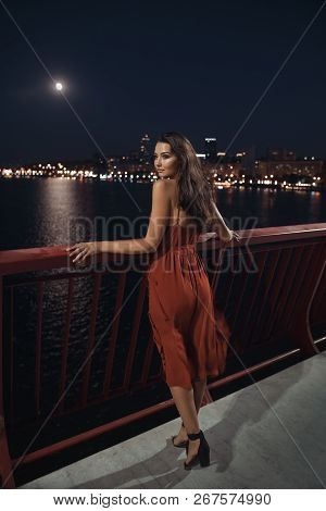 Young Ellegant Woman Standing On The Ligths Of The Night City Background On Bridge. Sexy Romantic Be