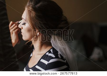 Makeup Artist Doing Brows And Applying Eyeshadow On Bride Face Close-up. Stylish Bride Getting Her M