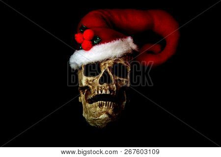 Evil Christmas Skull. Human Skull with a Santa Claus Hat. Isolated on black. Room for text. Evil Claus.