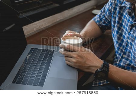 Business Man Dringking Coffee In Cup While Working On Laptop Computer. Close Up Hand Holding Coffee 