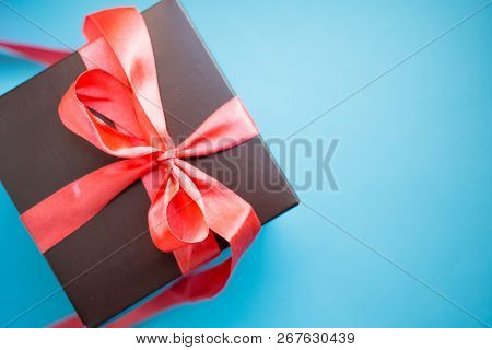 Brown Gift Box With Red Ribbon On Blue Background. Top View With Copy Space.