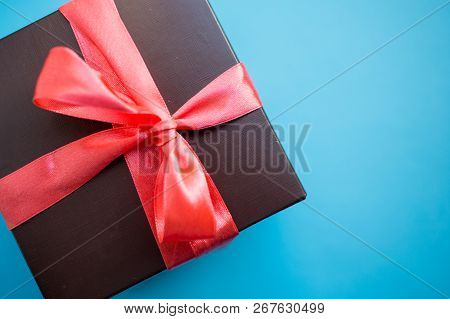 Brown Gift Box With Red Ribbon On Blue Background. Top View With Copy Space.