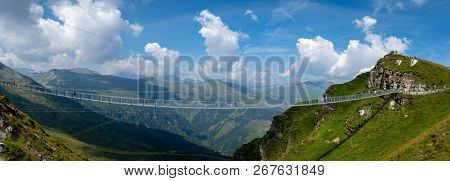 People Cross A Suspension Bridge, Stubnerkogel. The 140 M Long And One Metre Wide Bridge Was Built A