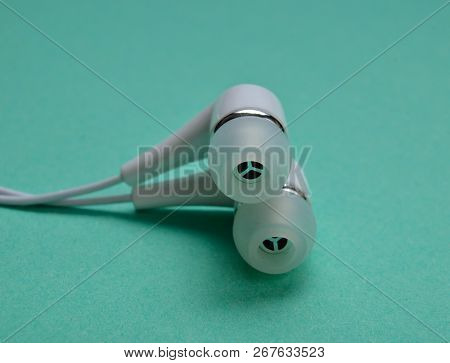 White Vacuum Headphones Close-up On A Mint Colored Background.