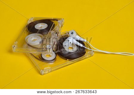 Retro Technology. Plastic Transparent Audio Cassette And White Vacuum Headphones On A Bright Yellow