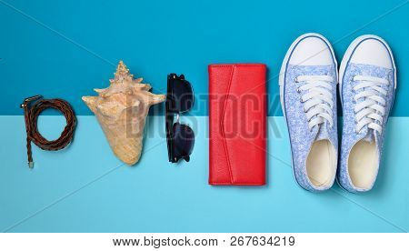 Women's Shoes And Travel Accessories On A Blue Pastel Background. Bag, Purse, Sneakers, Shell, Belt.