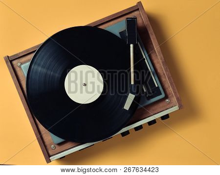 Vintage Vinyl Turntable With Vinyl Plate On A Yellow Pastel Background. Entertainment 70S. Listen To