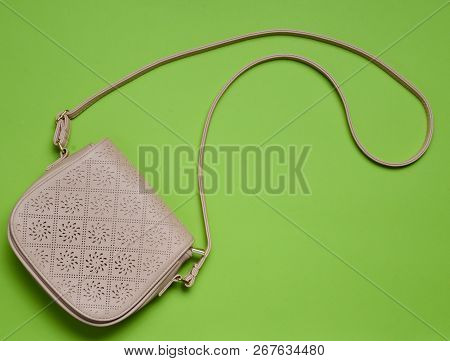 Beige Leather Bag On A Long Strap On A Green Pastel Background. Women's Accessories. Top View.