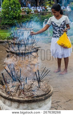Kandy, Sri Lanka - July 19, 2016: White Clothed Buddhist Devotee Lights Incense Sticks At The Temple