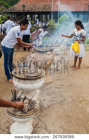 Kandy, Sri Lanka - July 19, 2016: White Clothed Buddhist Devotees Light Incense Sticks At The Temple