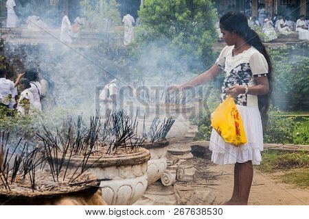 Kandy, Sri Lanka - July 19, 2016: White Clothed Buddhist Devotee Lights Incense Sticks At The Temple