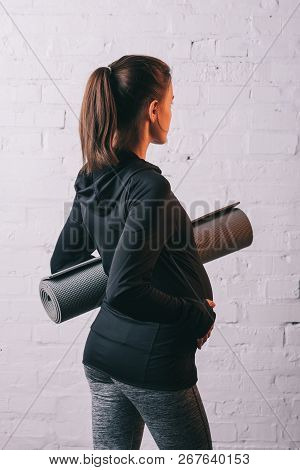 Back View Of Athletic Pragnant Woman With Sports Mat
