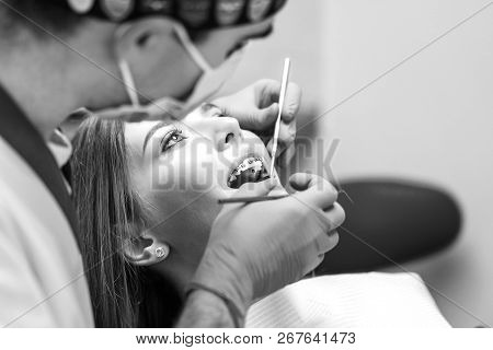 Dentist Examine Female Patient With Braces In Denal Office.
