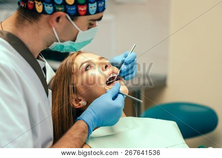 Dentist Examine Female Patient With Braces In Denal Office.