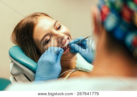 Dentist Examine Female Patient With Braces In Denal Office.