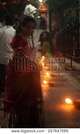 Pune, India - November 2018: A Woman Lights Up Lamp In Front Of A Temple Where Many People Have Gath