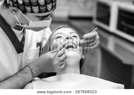 Dentist Examine Female Patient With Braces In Denal Office.