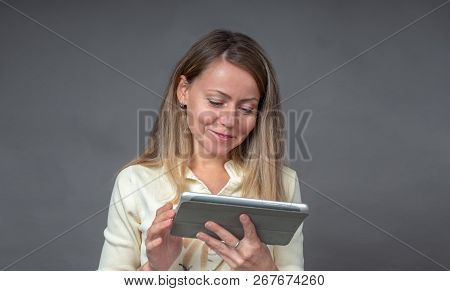 Portrait Of European Woman With Tablet Isolated On Gray Background. Smiling, Cheerfully, Joyfully Bl