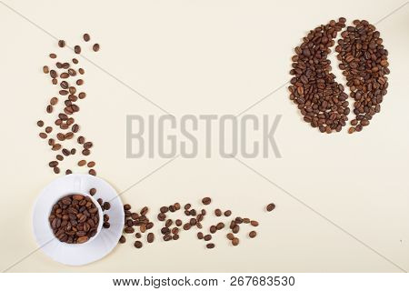 Roasted Brown Coffee Beans Laid Forming A Shape Of A Big Coffee Bean Next To Beautiful White Porcela