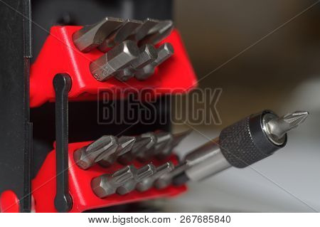 Bits Holder In Box And Many Tool Bits On White Background. Close-up View. Red Element In Plastic Box