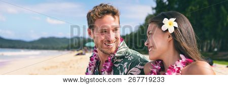 Hawaii tourists couple on beach vacation wearing lei necklace and flower for luau dance party. Tropical background banner travel lifestyle.