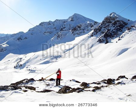 Człowiek w alpenhorn w górach w pobliżu Scuol, Szwajcaria