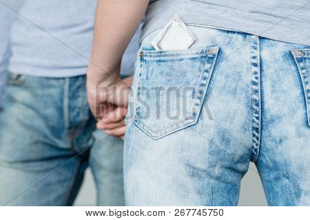 Safe Sex. Condom As A Pregnancy Prevention. Backview Of A Woman With A Contraceptive In Her Jeans Po
