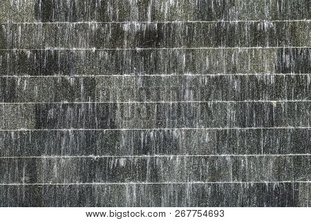 Surface Picture Of Black Stone With Flowing Water At  Artificial Waterfall.