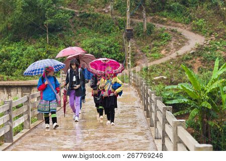 Sa Pa, Vietnam-december 13, 2013. Group Of Black Hmong Women With Tourists Walks On The Bridge Leadi
