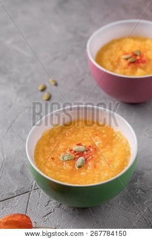 Pumpkin Soup Puree In Ceramic Bowls On A Gray Textured Background.