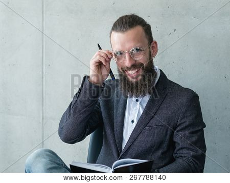 Smiling Professor Or Examinator. Bearded Man In Suit Jacket Rearranging His Glasses
