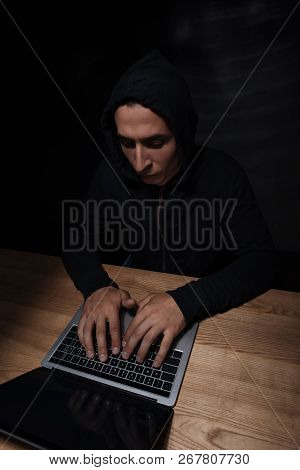Concentrated Hacker Using Laptop At Wooden Tabletop, Cuber Security Concept
