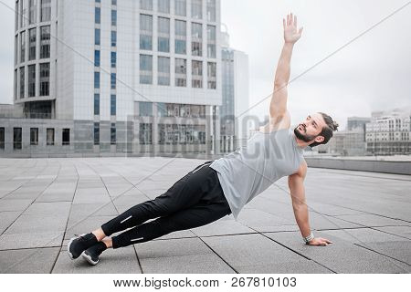 Picture Of Sportsman Stratching Up His Hand. He Holds On One Hand And Makes His Body Be Straight. Yo
