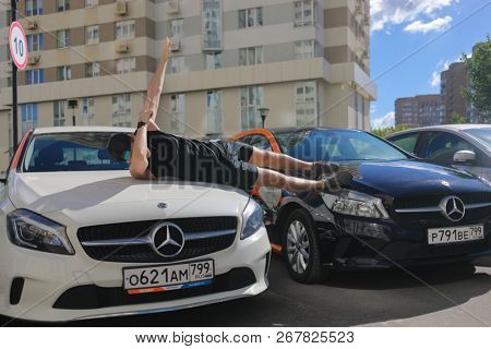 MOSCOW - JUN 20, 2018: Man (with MR) makes dab gesture and lies on two Mercedes Benz cars of Moscow carsharing company You drive, carsharing is system of short-term car rental