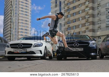 MOSCOW - JUN 20, 2018: Guy (with MR) jumps near two Mercedes Benz cars of Moscow carsharing company You drive, carsharing is system of short-term car rental