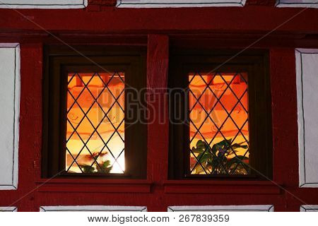 The Beam Construction And Wooden Framework Of A Half-timbered House At Night With A Lighted Stained-