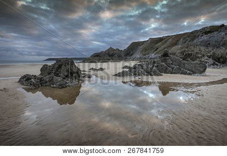 Jagged Landscape And Beach Pool Reflections On Three Cliffs Bay Looking Towards The Great Tor And Ox