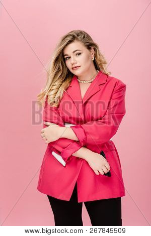 Attractive Young Plus Size Woman In Stylish Pink Jacket Looking At Camera Isolated On Pink