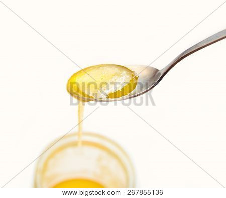 A Metal Spoon With Bee Honey Close-up Isolated On White Background