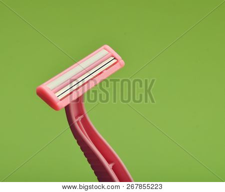 Pink Disposable Razor For Depilation On A Green Background.