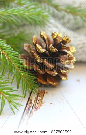 Christmas Card, Close - Up Of A Pine Cone Covered With Gold Sequins, Branches Of Green Spruce On A W
