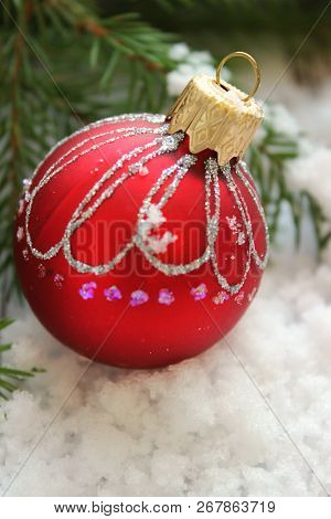 Christmas Card, Close-up Christmas Toy Red Ball With Shiny Pattern On The Snow Surrounded By Fir Bra